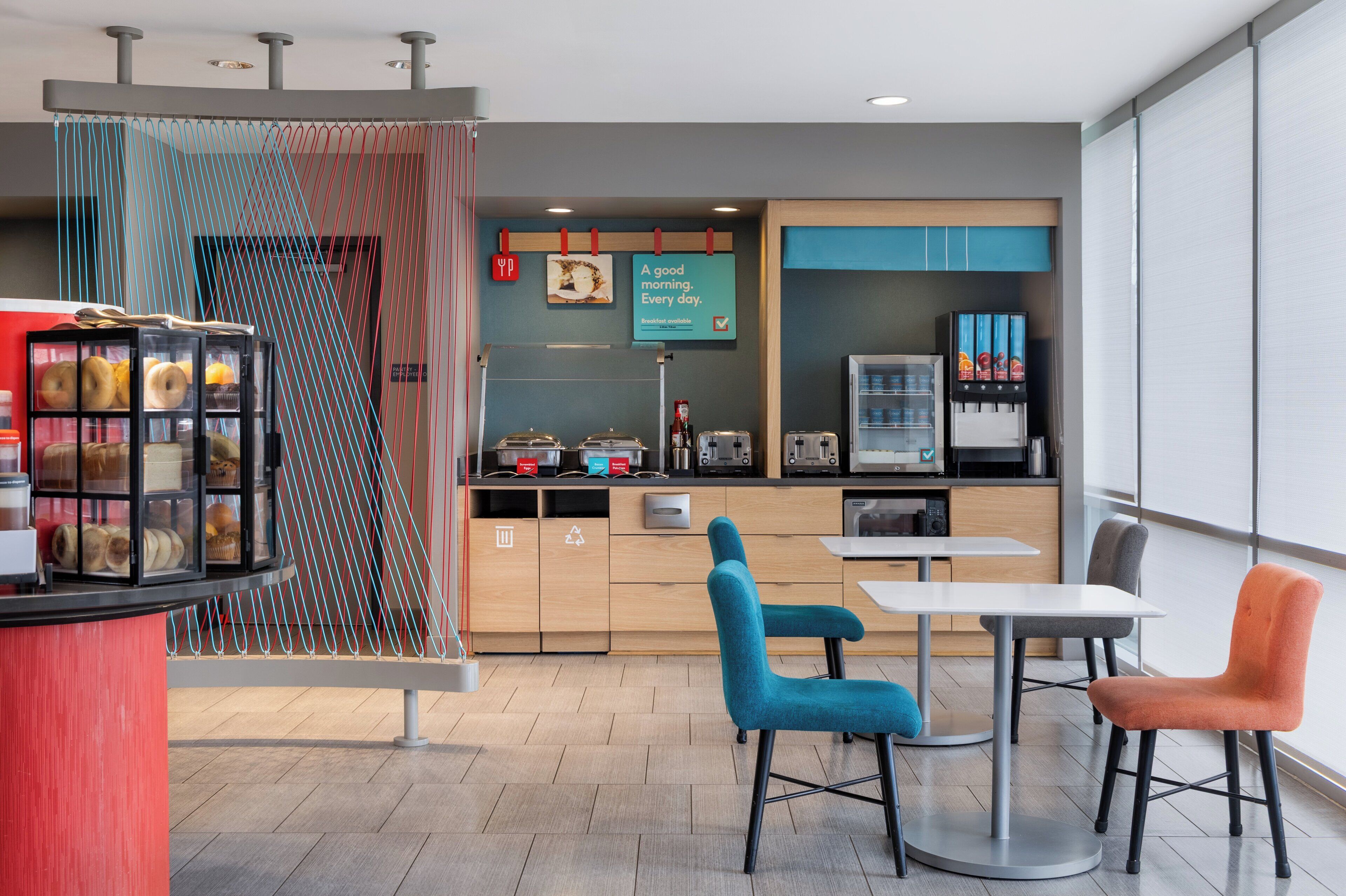 A modern kitchen with a breakfast bar, a coffee machine, and a seating area with chairs.