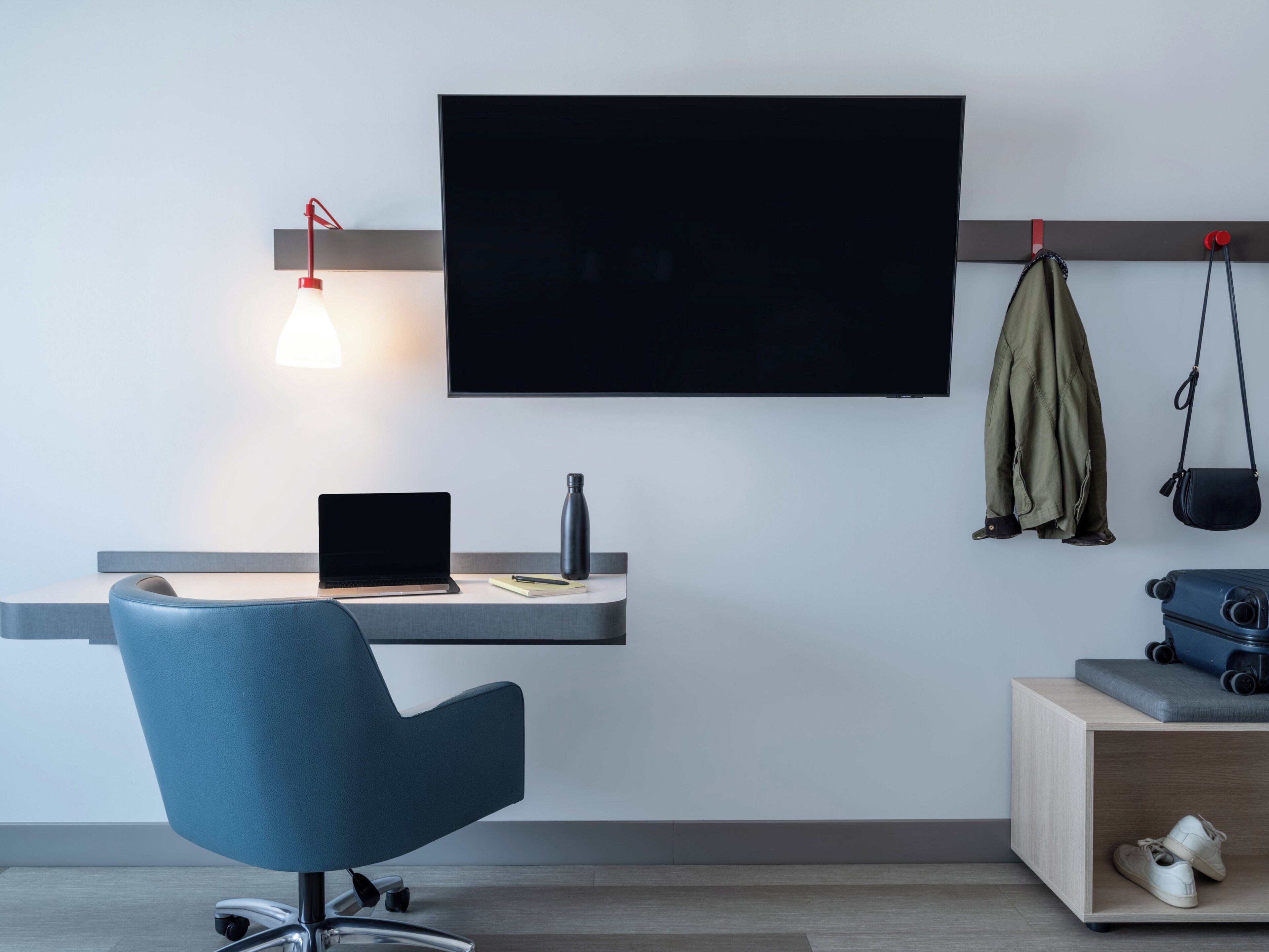 Un espacio de oficina moderno con un escritorio, una silla y un televisor montado.