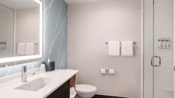 Un baño moderno con un espejo grande, un lavamanos, un inodoro y una cabina de ducha de vidrio.