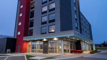 A modern hotel building with a prominent 'QVIID' sign, a glass entrance, and a red accent wall.