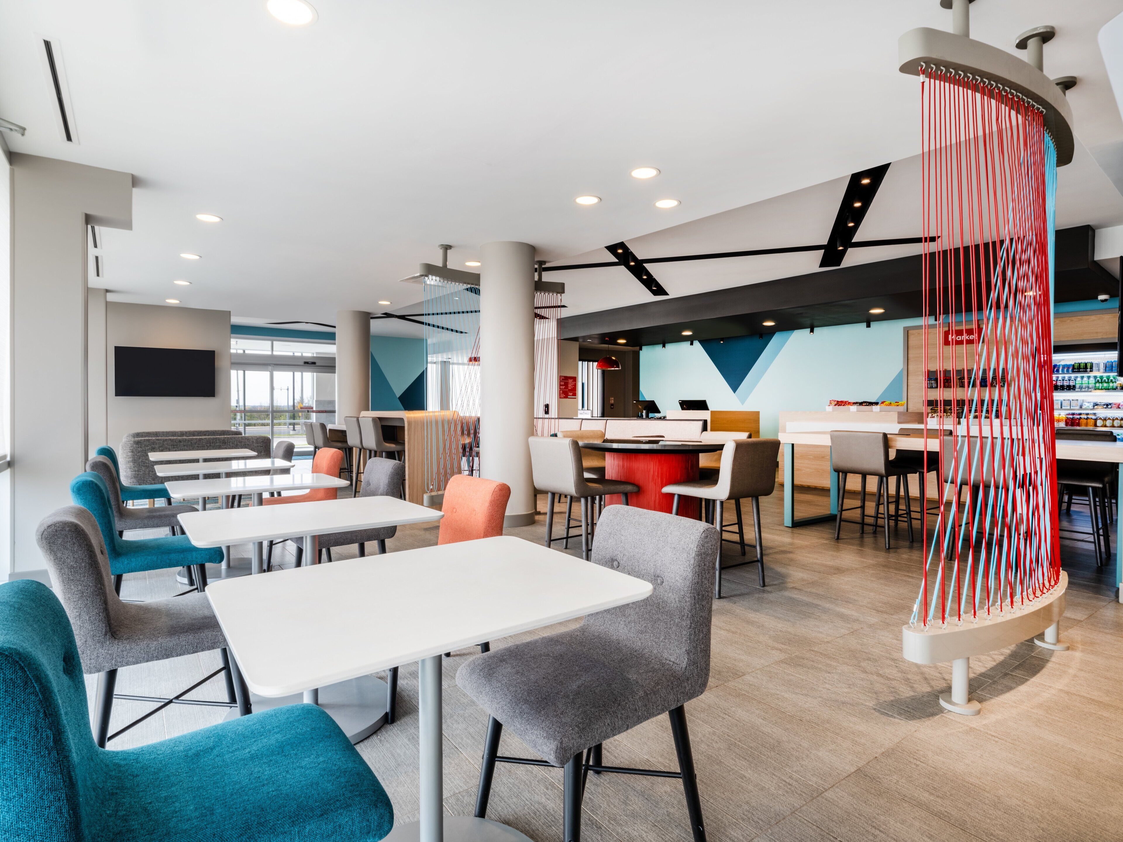 A modern cafe with tables and chairs, a bar area, and a large decorative column.