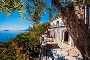 A coastal property with a stone terrace, outdoor seating, and a view of the sea. - Villa Raissa luxury Property in Positano with private jacuzzi (Positano)