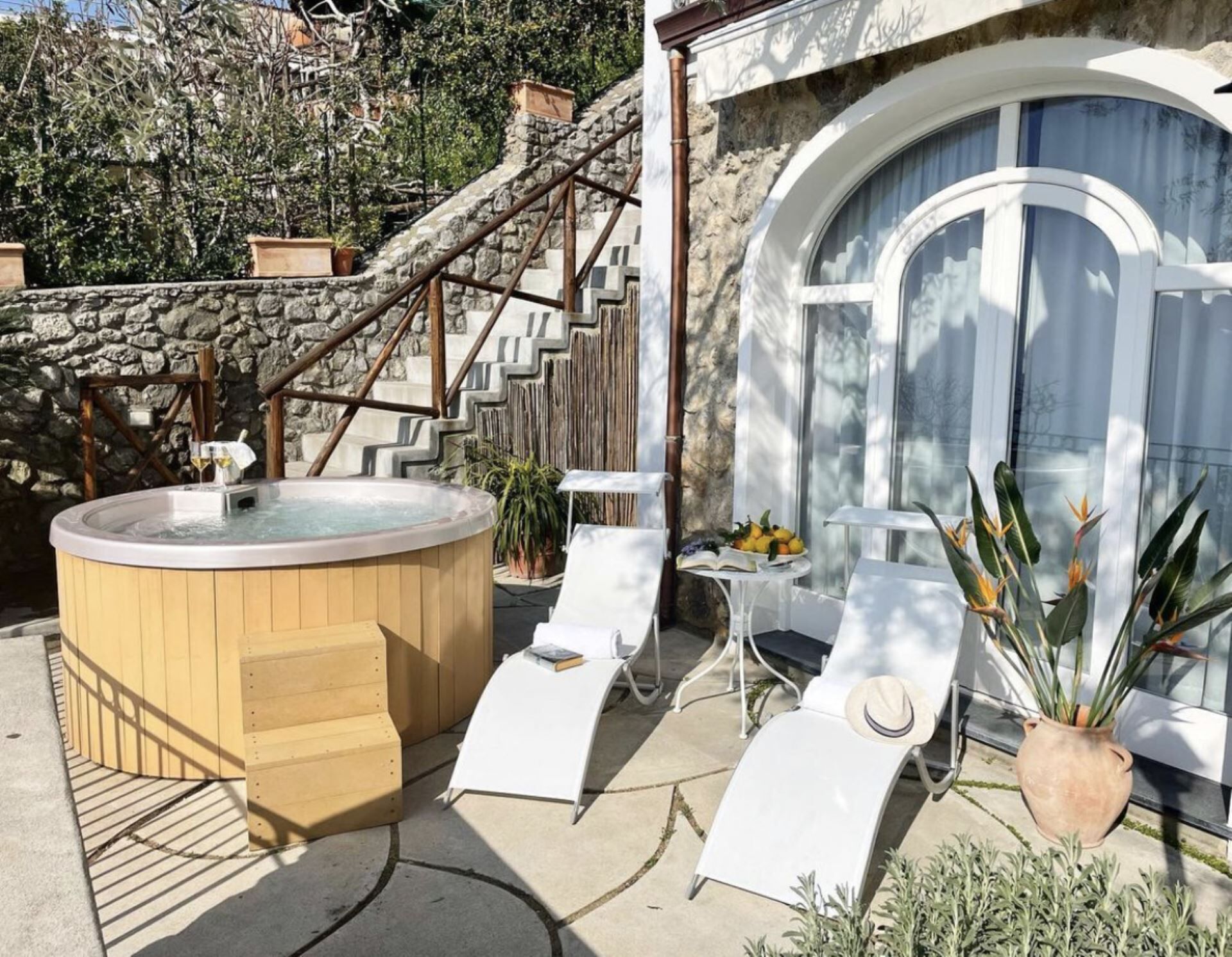 Een hottub, buiten zitplaatsen en een trap naar een stenen gebouw.