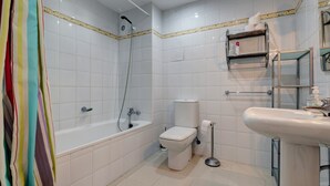 Een badkamer met een bad, toilet, wastafel en douche.