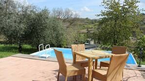 An outdoor pool area with wicker furniture and a view of the surrounding landscape. - Country House near Rome (Castel Madama)