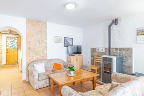 Un salon avec un canapé, une table en bois, un téléviseur et une cheminée.