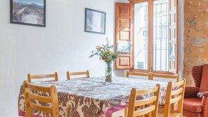 En spiseplads med et rundt bord, stole, en vase med blomster og to billeder hængende på væggen.