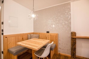 Un coin salon avec une table et un banc en bois, un luminaire suspendu et un mur à texture.