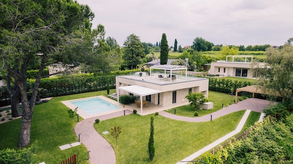 A modern house with a swimming pool, a covered patio, and a well-maintained garden.