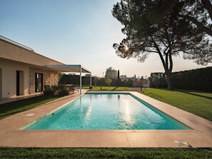 Una piscina con facciata in pietra, un patio coperto e vista sullo skyline urbano.