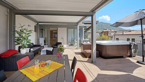 Un patio al aire libre con una mesa, sillas, un jacuzzi y una zona de estar cubierta.
