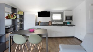 Una cocina compacta con zona de comedor, un televisor de pantalla plana y un ventanal.