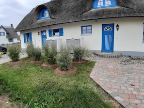 A traditional house with a thatched roof, blue shutters, and a paved entrance. - 3-room vacation home (6 persons) Luv - Holiday homes Luv and Lee OVS 106 with sauna (Zierow)