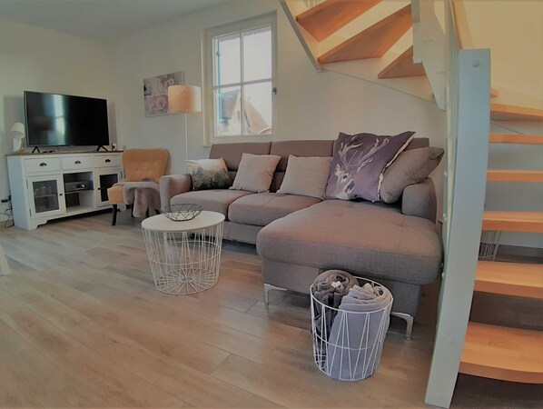 A modern living room with a sofa, TV, and a staircase. - 3-room vacation home (6 persons) Luv - Holiday homes Luv and Lee OVS 106 with sauna (Zierow)