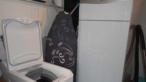 Un espacio pequeño con lavadora, plancha y refrigerador.