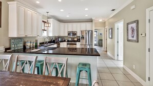 A spacious kitchen with white cabinets, a central island, and a dining area with stools.