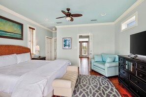 A bedroom with a large bed, a ceiling fan, a TV, a light blue sofa, and a patterned rug. - 5min Walk to Beach • Private Pool, Rooftop Deck | A Piece of Heaven by AvantStay (Santa Rosa Beach)