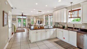 A spacious kitchen with white cabinets, a large island, and a dining area.