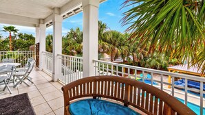 A covered outdoor area with a pool, lounge chairs, and a wooden bench.
