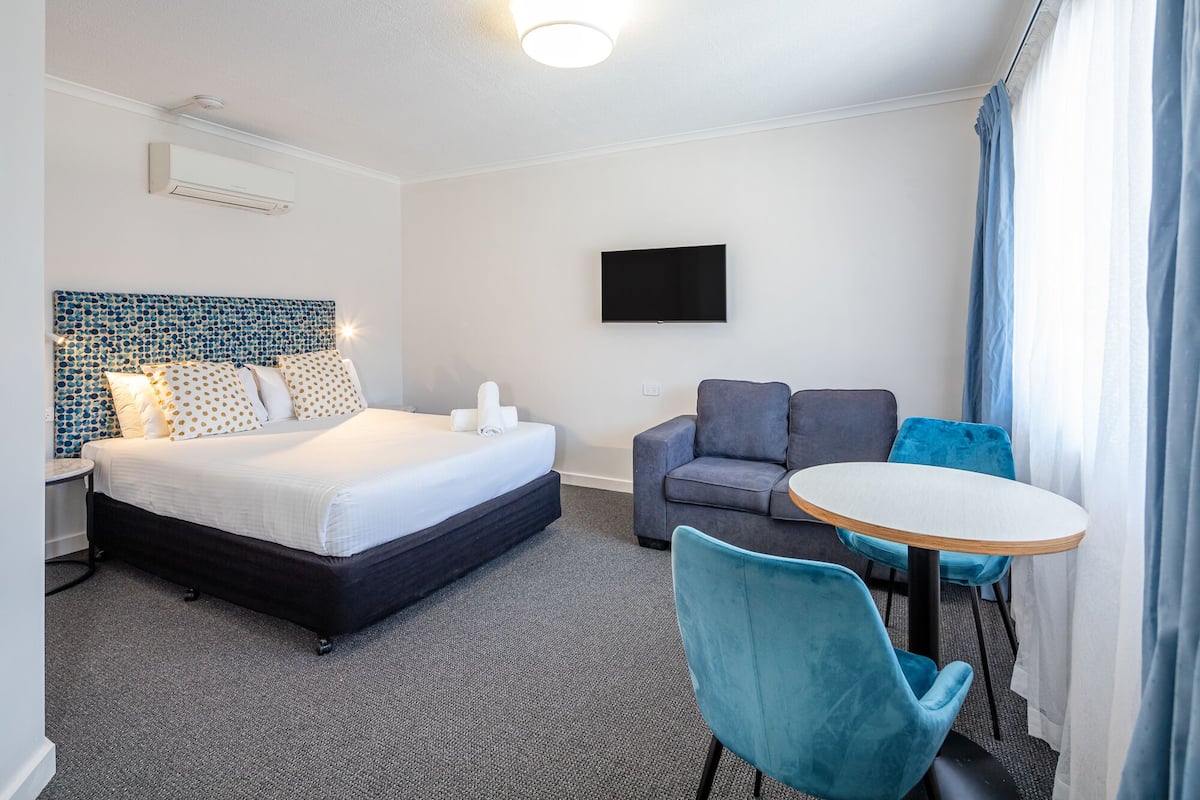 A hotel room with a bed, a sofa, a TV, and a table.