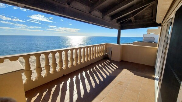 A balcony with a view of the sea, a tiled floor, and a railing.