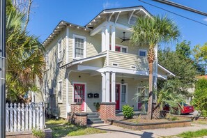 Stunning two-story home with a central entrance, balcony, and beautifully manicured front yard.