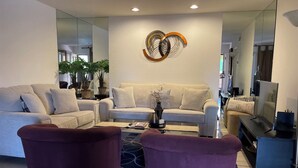 A modern living room with a sofa set, two armchairs, a coffee table, and a TV. - Three Pools. Mountain Views. Just Blocks from vibrant downtown nightlife! (Palm Springs)