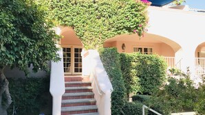 A building with a staircase leading to a door, surrounded by greenery and a blue awning. - Three Pools. Mountain Views. Just Blocks from vibrant downtown nightlife! (Palm Springs)