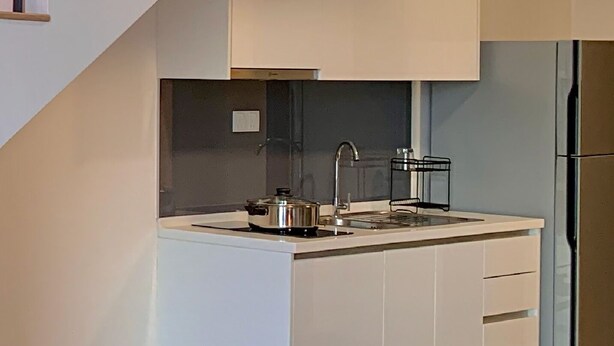 A modern kitchen with a built-in island, stainless steel appliances, and a staircase with wooden steps. - Eclipse Residency, Cyberjaya by Flexihome MY (Cyberjaya)