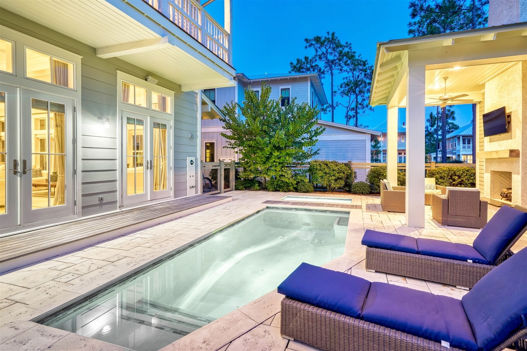 A modern house with a swimming pool, outdoor seating, and a covered patio area.