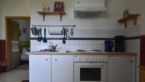 Una cocina compacta con horno integrado, cafetera y utensilios colgantes.