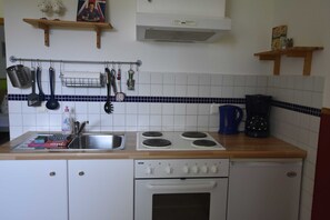 A kitchen with a stove, oven, and various utensils. - Vacation apartment upstairs in the red house on the Baltic Sea cycle path OVS 103 - 2-room vacation apartment (Blowatz)