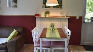 Una mesa de comedor con sillas, una lámpara colgante, una planta pequeña y un cuadro en la pared.