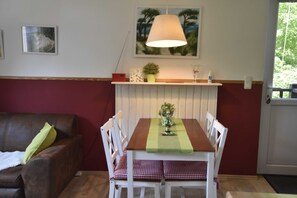 A dining table with chairs, a hanging lamp, a small plant, and a framed picture on the wall.
