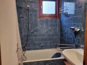 A bathroom with a bathtub, a shower, and a window.