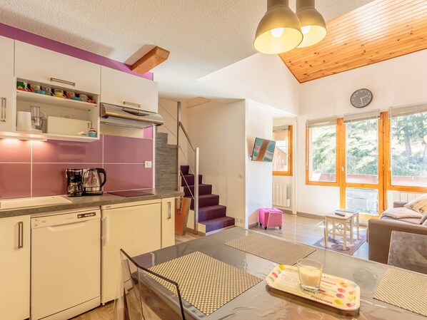 Een moderne keuken met een eethoek, houten plafond en grote ramen.