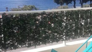 A balcony with a view of the sea, a metal chair, and a white railing. - BRILOC Apartment (48 m² - 48 sq ft - ) (Ajaccio)