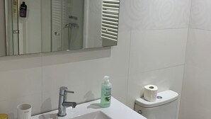 Un bagno con lavandino, specchio e water bianchi.