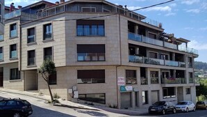Un edificio a più piani con balconi, un cartello che indica 'ULTIMAS VIVIENCIAS' (ultimi appartamenti) e un'area di parcheggio con diverse auto.