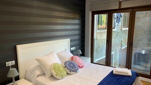 Una camera da letto con un letto, un comodino, una lampada, una finestra con vista e una porta che dà su uno spazio esterno.