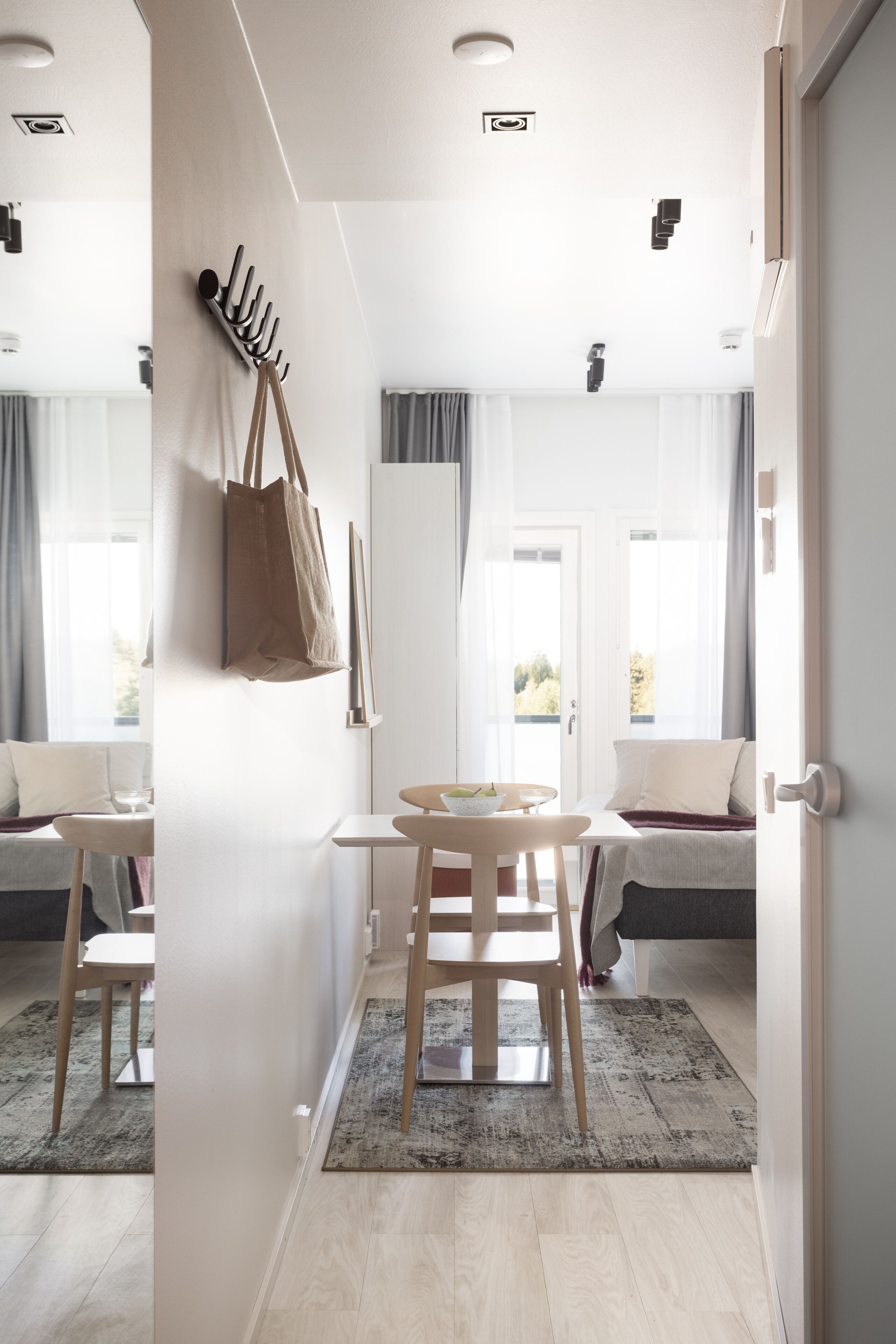 Une pièce moderne avec une table en bois, des chaises, un canapé et une grande fenêtre avec des rideaux.