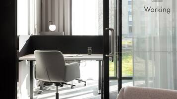 A modern office space with a desk, office chair, and a glass partition.