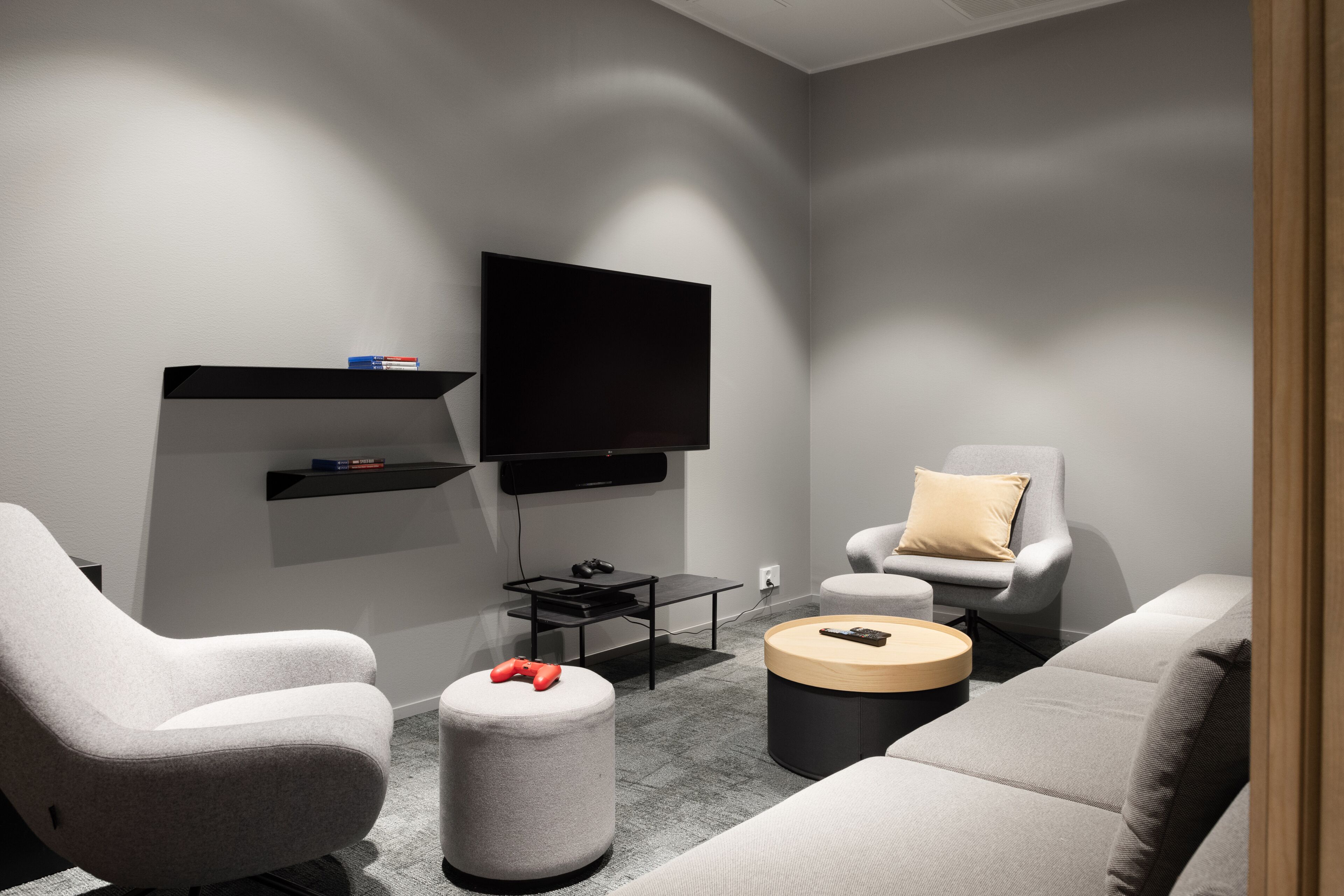 Una sala de estar moderna con televisor de pantalla plana, sofás grises, una mesa de centro y una silla gamer.