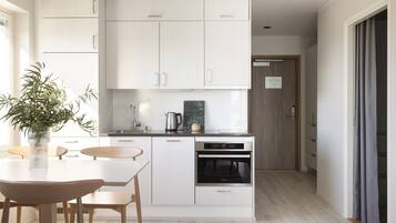 Una cocina moderna con armarios blancos, horno empotrado y comedor con mesa y sillas.