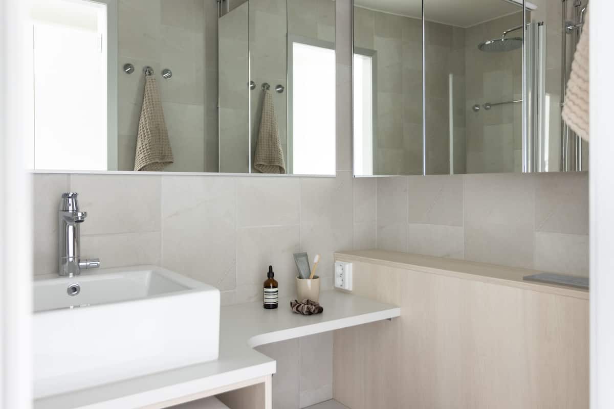 Ein modernes Badezimmer mit Waschbecken, Spiegel und Duschbereich.
