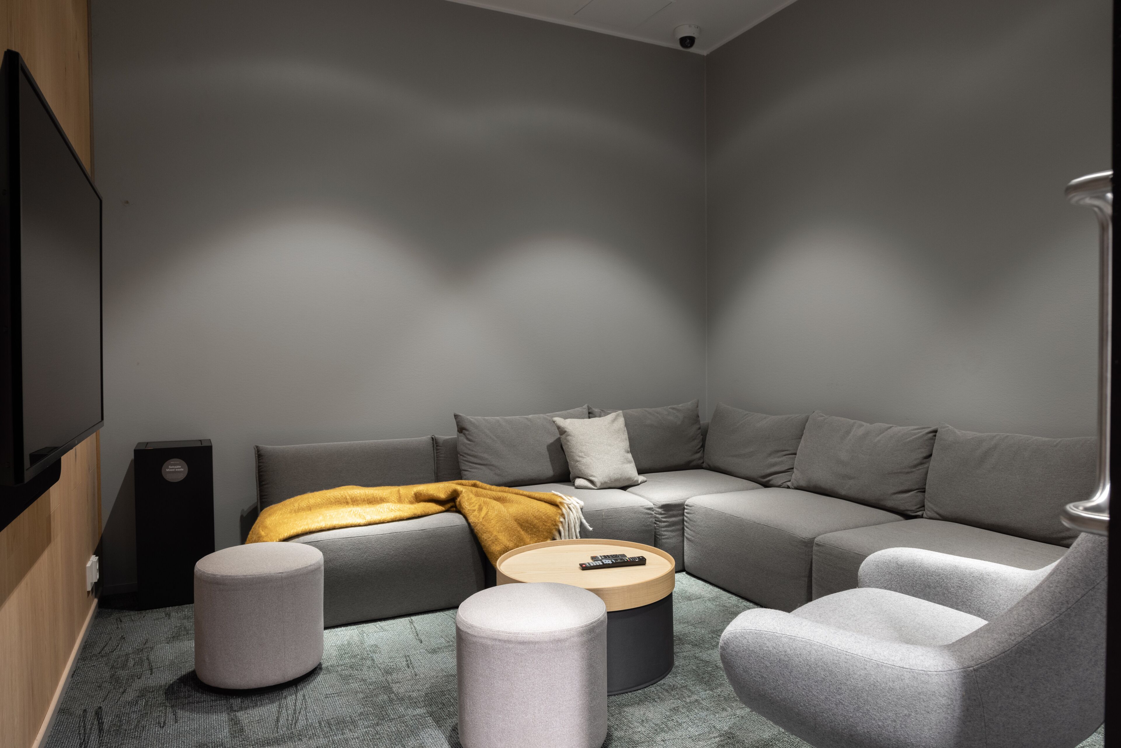 A modern living room with a grey sectional sofa, ottomans, a coffee table, and a mounted TV.