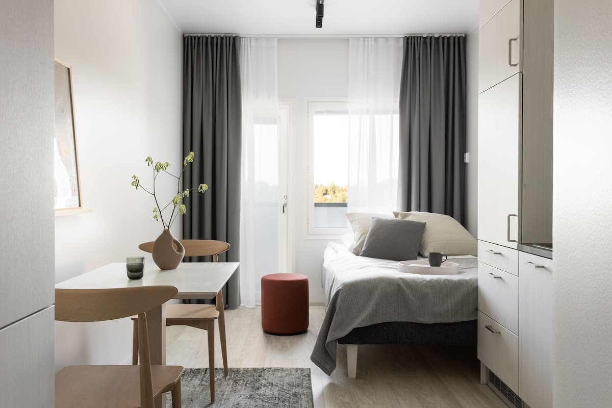 Ein modernes Schlafzimmer mit Bett, Nachttisch, Stuhl und einem kleinen Tisch mit einer Vase.