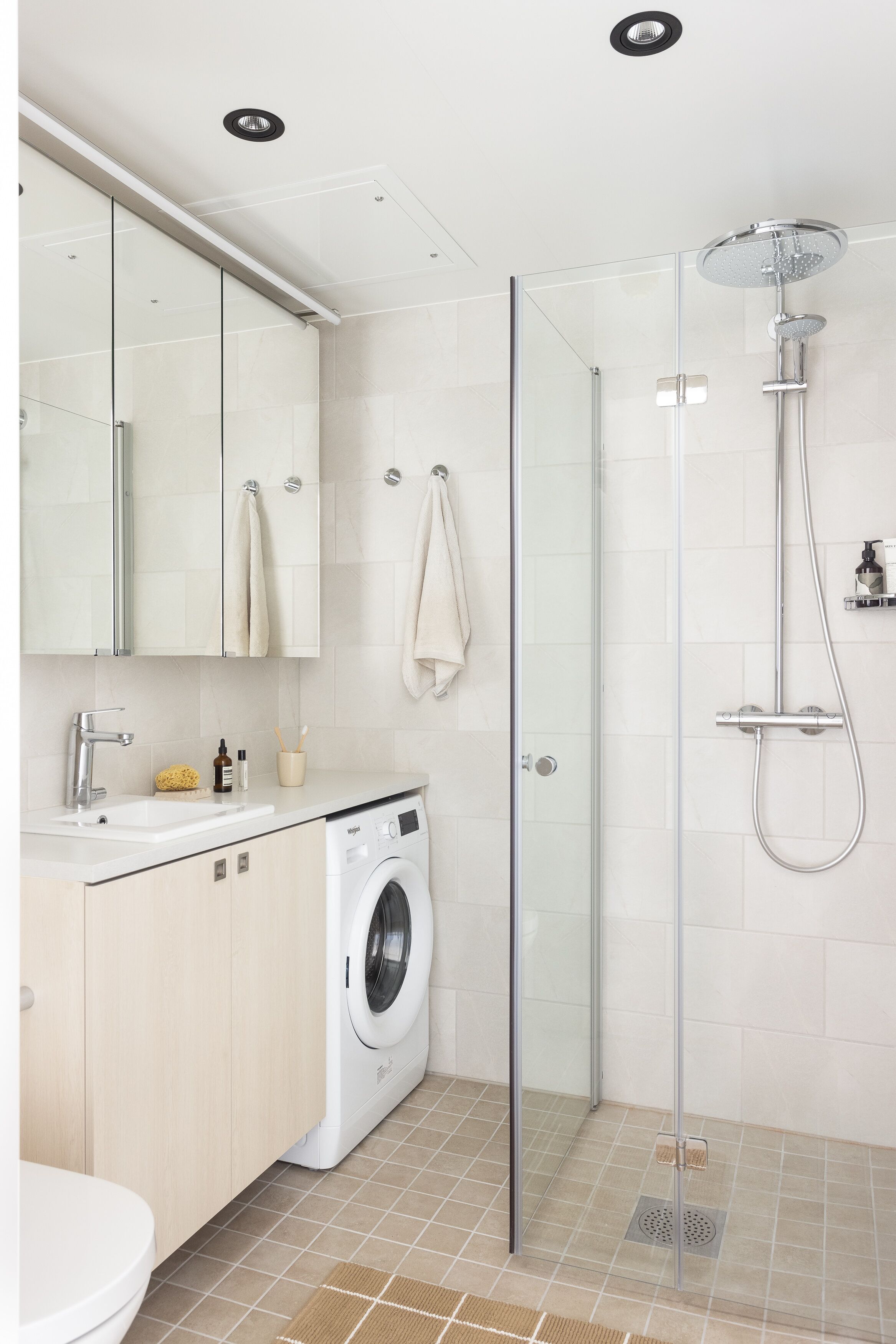 Un baño moderno con cabina de ducha de vidrio, lavadora e inodoro.