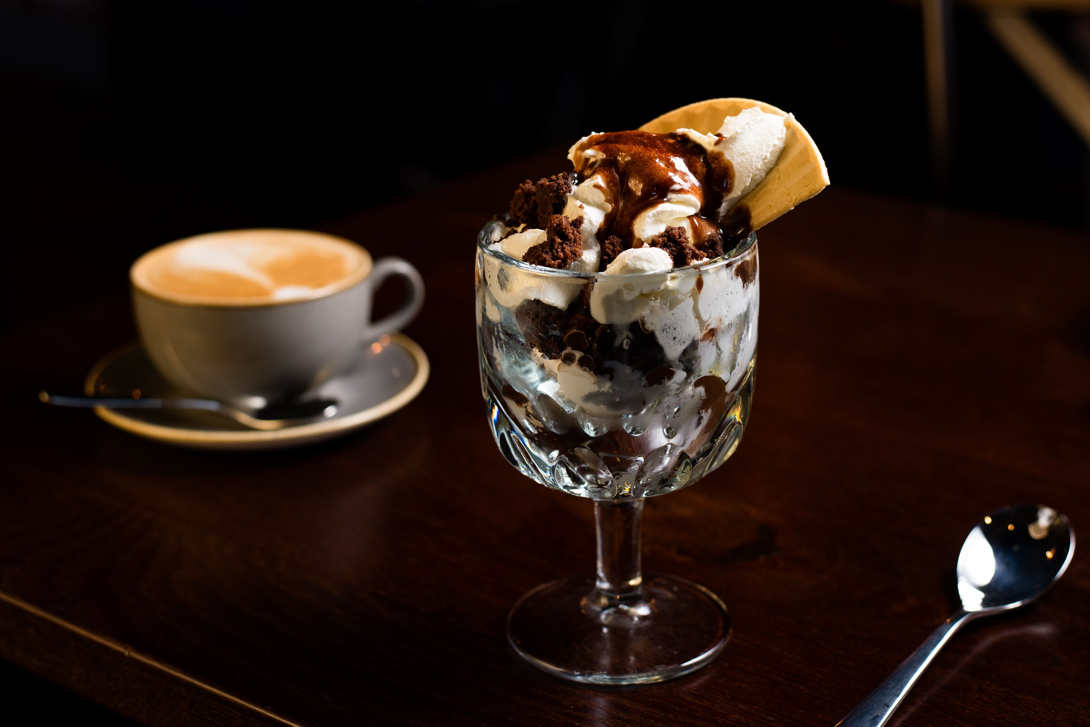 Postre en vaso con cuchara y platillo a un lado.