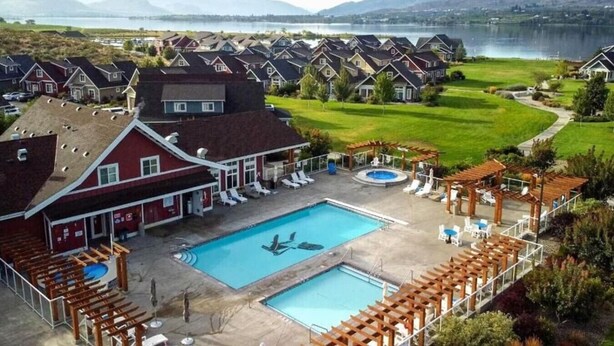 A residential area with a swimming pool, lounge chairs, and a view of a lake and mountains. - View - Beautiful home - 2 kitchens #198 (Osoyoos)